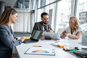 Business people working together on a project using laptops and charts in office meeting room