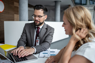 Businessman typing on laptop while discussing with female colleague