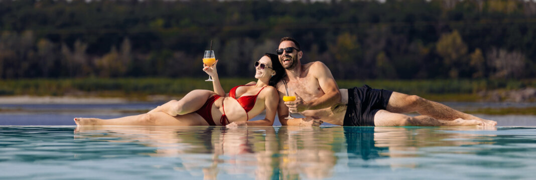 A man and a woman enjoy each other's company and relaxation at the resort pool with cocktails. The concept of relaxation is relaxation and joyful moments.