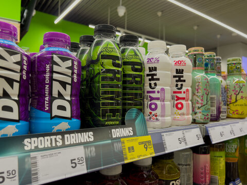Poznan, Poland - July 5, 2025: DZIK and PRIME vitamin drinks alongside OYI CHE coconut water bottles displayed neatly on a colorful retail supermarket shelf