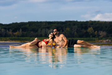 Couple enjoying their vacation and each other's company at a resort pool with cocktails. Concept...