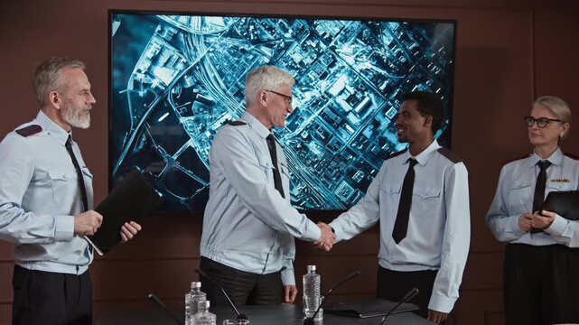 Wide shot of senior Caucasian commander in uniform giving handshake to black male colleague after discussion in center with navigation map during military conference with team