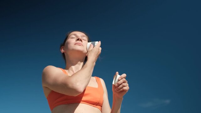 A low angle shot of a woman protecting her face with sunscreen stick