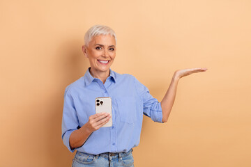 Confident senior woman with short white hair smiling and gesturing while holding a modern...