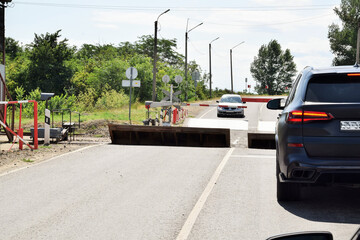 Cars are parked at a closed, controlled railway crossing