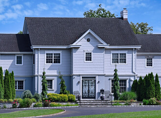 Two story suburban house with clapboard siding on the upper level