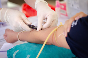 Close up nurse pricking needle syringe in the arm patient drawing blood sample for blood test ,...