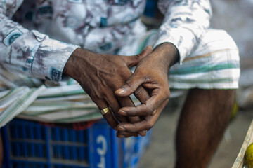An old man sits with his hands on his hips, deep in thought.