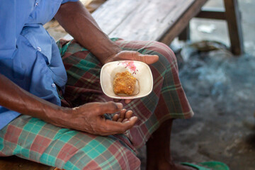 An old man eating street food at the market.