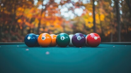 Colorful pool balls in a row on a teal table, autumnal background