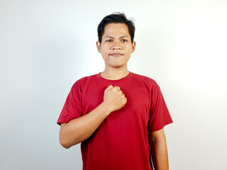 Portrait of a confident man wearing a red shirt, standing indoors, gesturing by placing his hand...