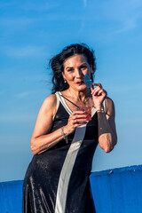 Elegant senior model enjoying a cocktail against blue sky