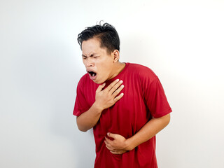 A man in a red shirt clutching his chest and stomach, conveying a sense of discomfort or illness,...