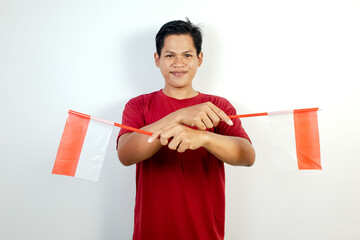 A young Asian man wearing a red shirt holding two national flags, expressing patriotism and pride...