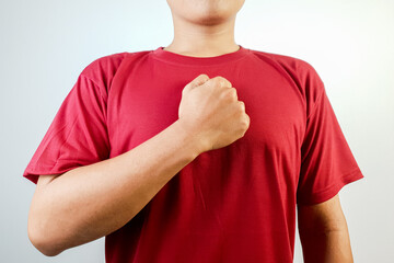 Portrait of a confident man wearing a red shirt, standing indoors, gesturing by placing his hand...