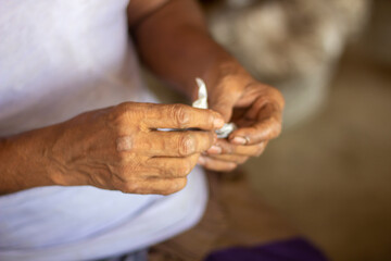 An old man holds a small paper with his both hands