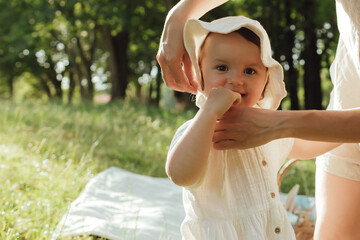 Happy young mother playing with her baby on the grass in a sunny park. Family bonding, early...