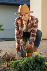 Cute young woman in straw hat planting the flowers in her garden