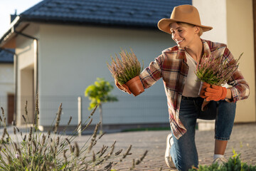 Cute young woman in straw hat planting the flowers in her garden