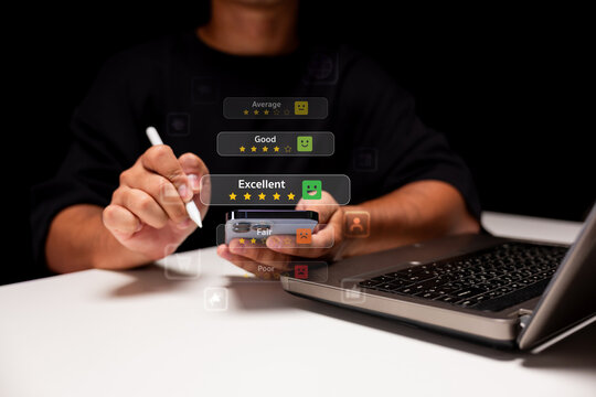 A person uses a stylus on a smartphone beside a laptop, interacting with digital rating emojis from poor to excellent on a dark background.