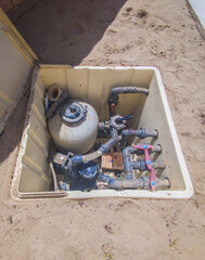 Buried mounted sewage treatment box. Beach sand covered surface