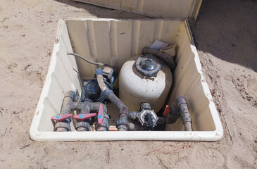 Buried mounted sewage treatment box. Beach sand covered surface