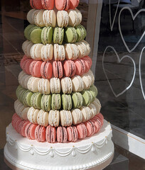A tiered macaron tower features alternating layers of pink, white, and green macarons arranged in a conical shape