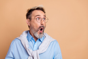 Portrait of a stylish mature man surprised with gray-streaked hair wearing glasses and a sweater...