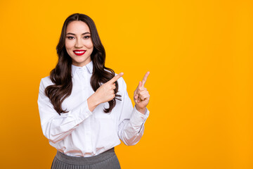 Confident young woman in formal attire gestures with both hands on a vibrant yellow background