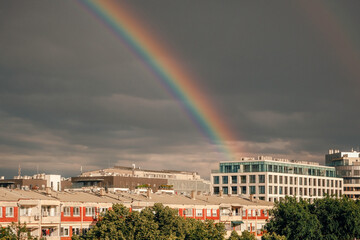 Rainbow arcs over city rooftops beneath stormy skies