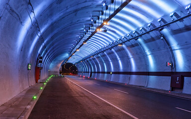 Illuminated modern road tunnel at night. Curved road tunnel lit with striking blue and white LED...
