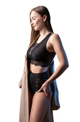 Studio portrait of a young slender girl in lingerie against a black background.