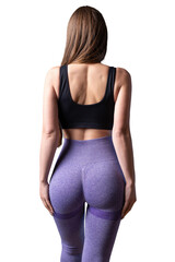 A young healthy girl in a sports top and leggings poses in the studio against a black background.