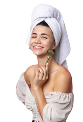 A beautiful cheerful attractive girl with a towel on her head holds a cosmetic roller near her face...