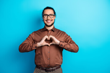 Young business professional in formalwear gesturing a heart symbol with hands on a teal background
