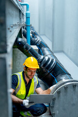 Vertical image side view of engineer or technician worker use laptop to check pipe system of factory building during raining.
