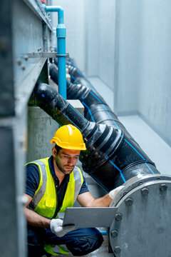 Vertical image side view of engineer or technician worker use laptop to check pipe system of factory building during raining.