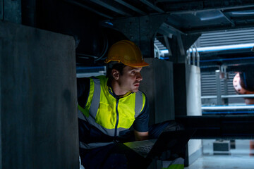 Engineer or technician worker use laptop to check pipe system of factory building also stay under the system structure.