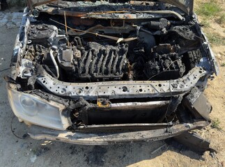 This image shows the severely burnt engine compartment and front end of a vehicle, indicating significant fire damage.