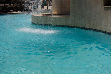 Sparkling blue pool water with fountain feature on a sunny day in a relaxing vacation resort