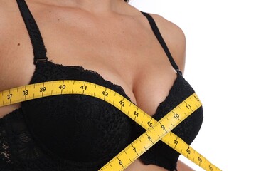 Woman in beautiful bra measuring breast circumference on white background, closeup