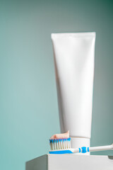 A toothbrush with blue and white bristles holds a dab of pink toothpaste in front of a dental care...
