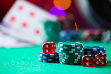 Casino chips and dice on green table against blurred lights, closeup. Space for text