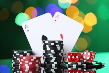 Casino chips, playing cards and dice on mirror surface against blurred lights, closeup