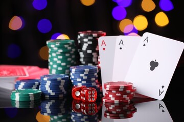 Casino chips, playing cards and dice on mirror surface against blurred lights, closeup