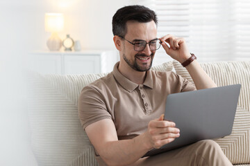 Professional psychologist having online consultation with his client via laptop on sofa indoors