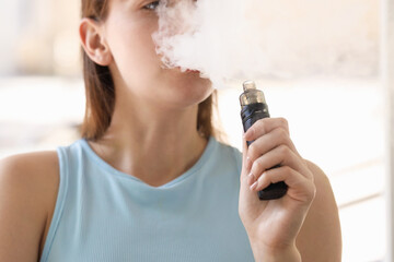 Young woman using electronic smoking device outdoors, closeup