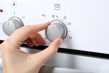 Maximum concept. Woman turning on oven, closeup