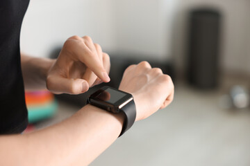 Woman checking fitness tracker during training indoors, closeup. Space for text