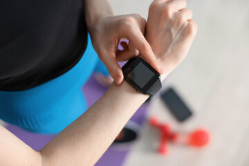 Woman checking fitness tracker during training indoors, above view